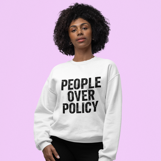 Person wearing a white sweatshirt with 'People Over Policy' text on a pink background