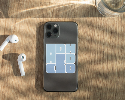 Phone with a case displaying ADHD CEO sticker, airpods, and a glass on a wooden surface
