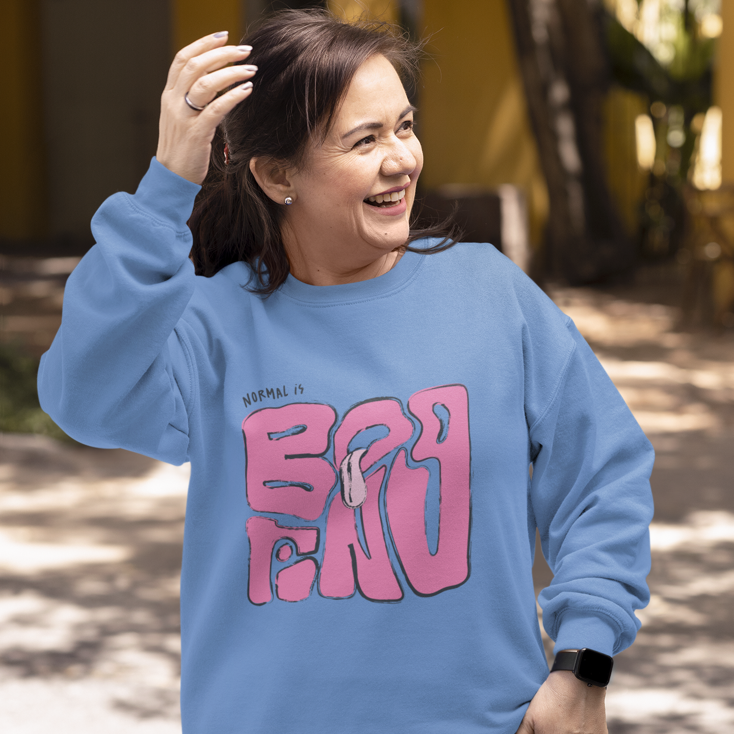 Person wearing a blue sweatshirt with pink text outdoors