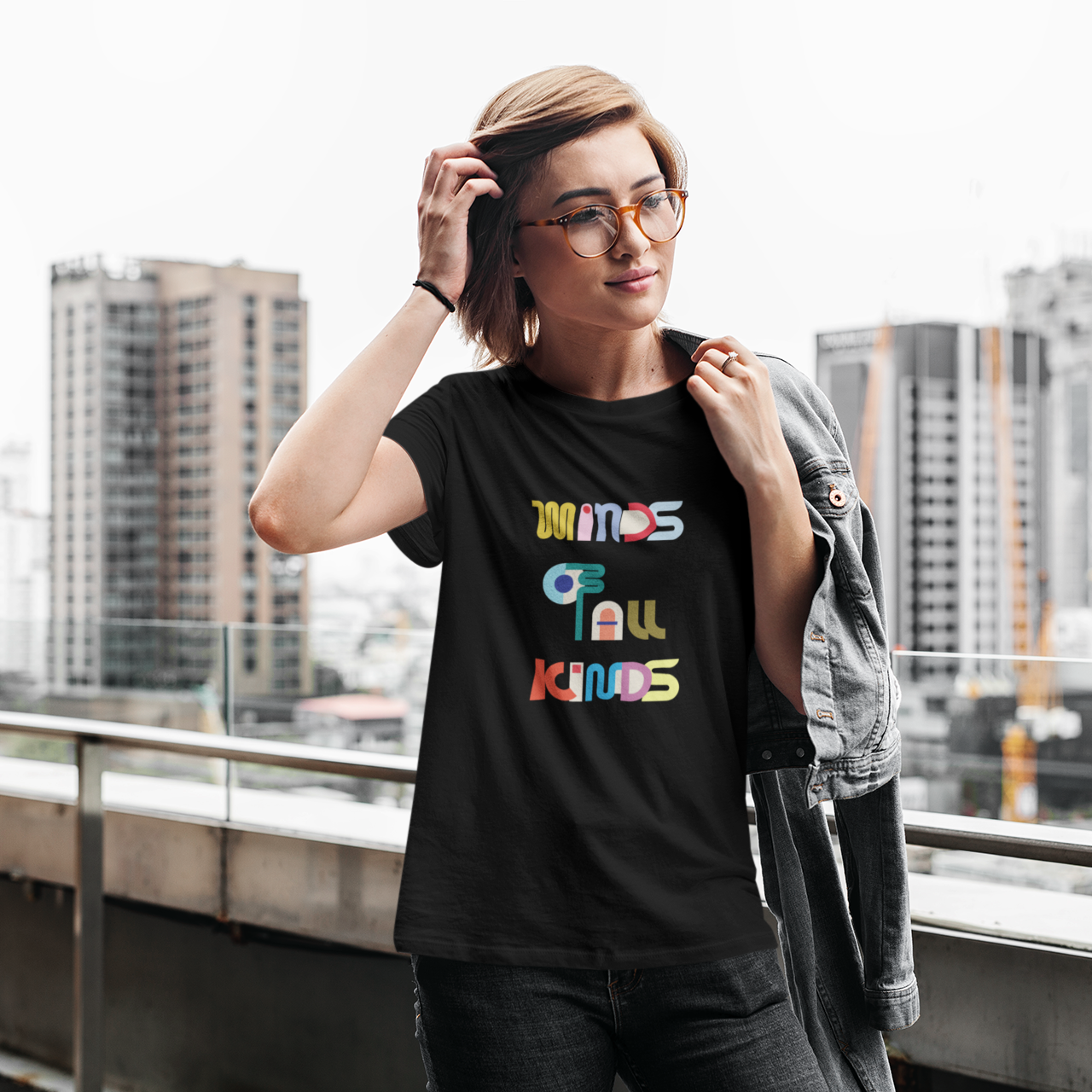 Person wearing a black t-shirt with colorful text on a rooftop with cityscape background
